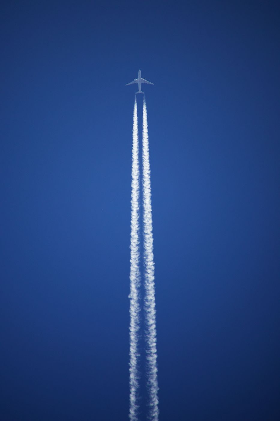 A plane and its contrail in a deep blue sky
